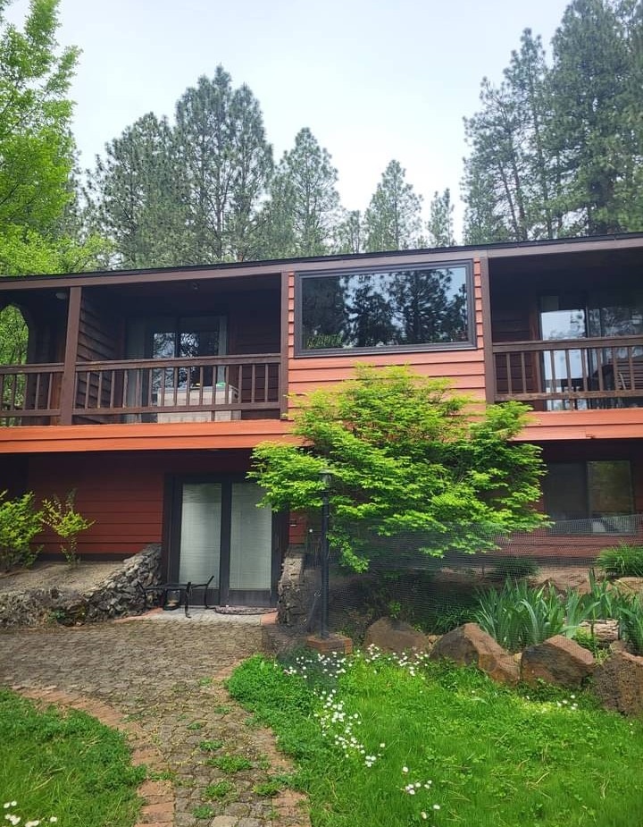 Brown house exterior painting with beautiful green landscaping and patio
