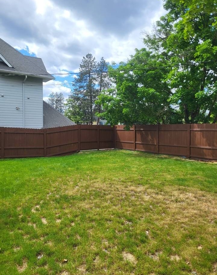 Wide view of a freshly stained wooden yard fence in Spokane